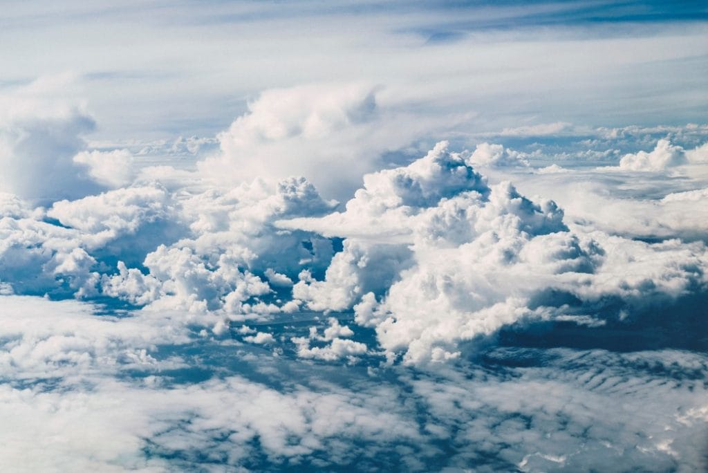 aerial view of fluffy white clouds against a blue sky, showcasing a serene cloudscape with layered textures