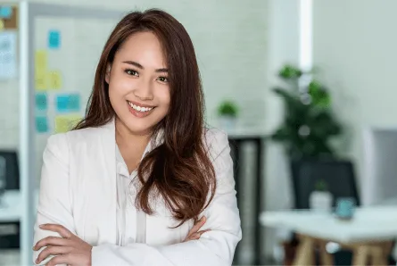 a confident woman in a white blazer stands with her arms crossed in a modern office setting filled with greenery and colorful notes